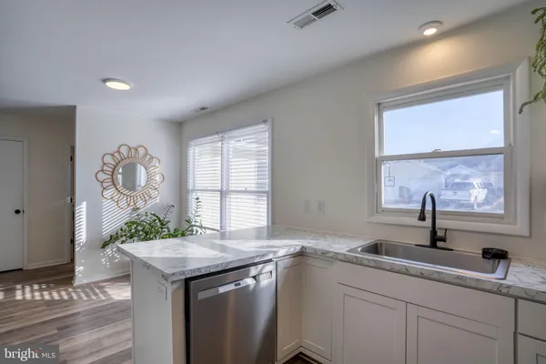 an open kitchen with a sink and dishwasher with wooden floor