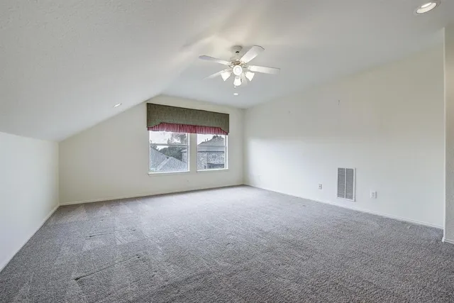 an empty room with windows and ceiling fan