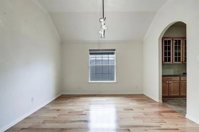 an empty room with wooden floor cabinet and windows