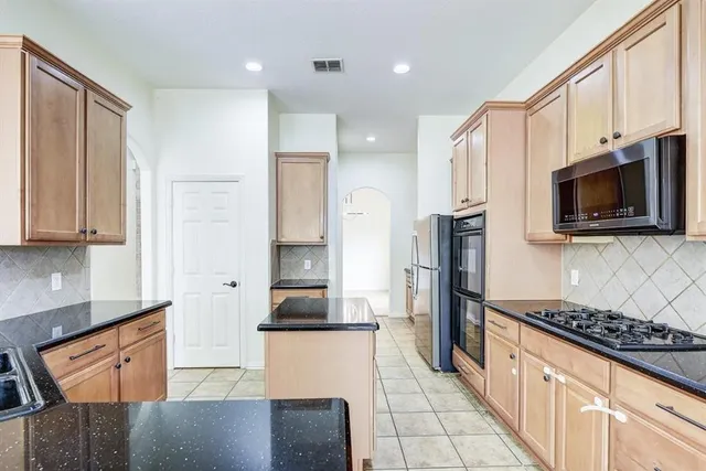 a kitchen with stainless steel appliances granite countertop a refrigerator and a stove top oven