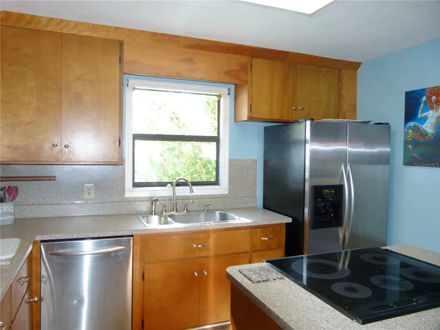 a kitchen with stainless steel appliances granite countertop a sink a refrigerator and a stove
