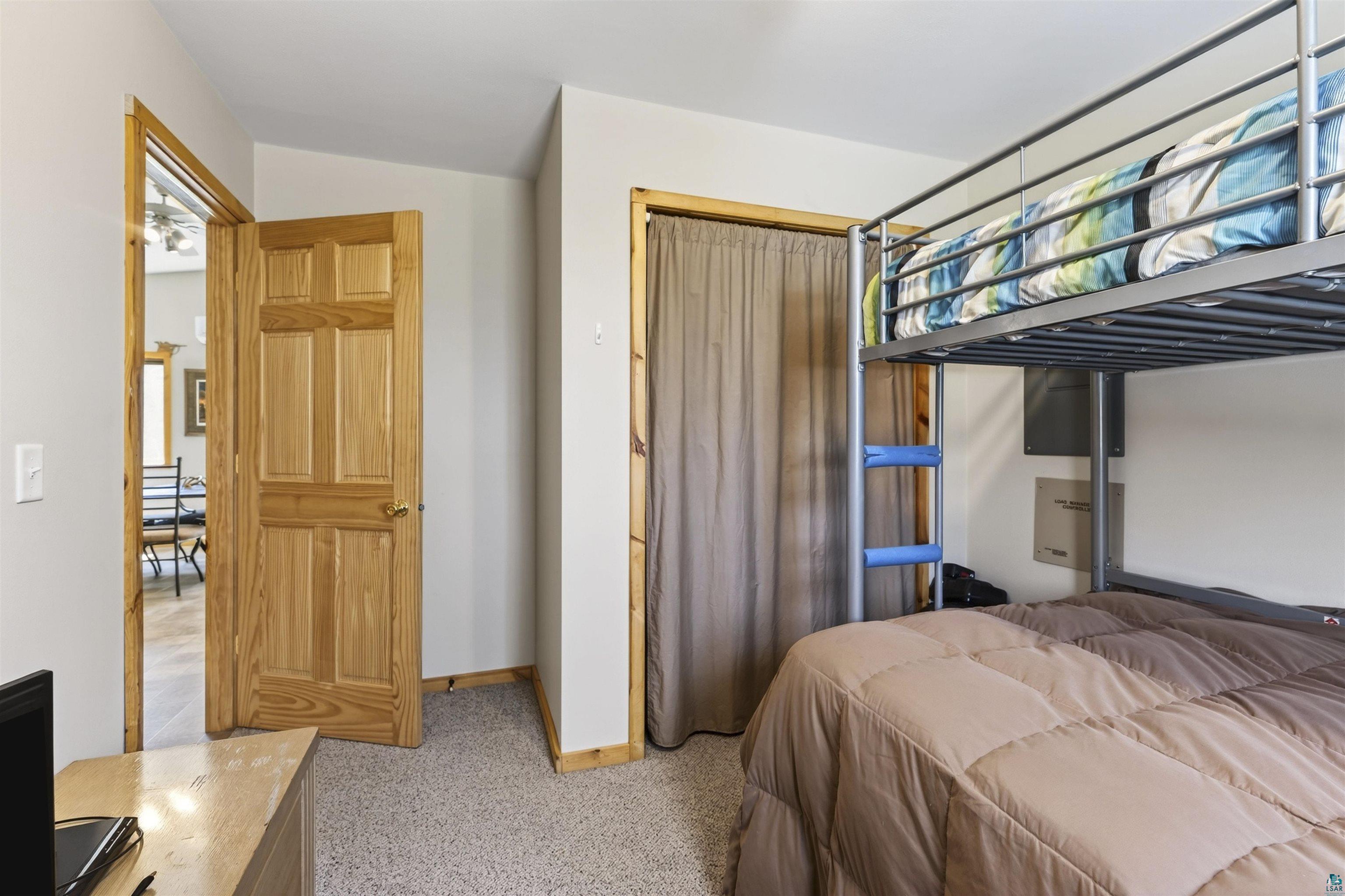 12235 East Crooked Lake Road Gordon, WI 54838 - Photo 29 of 48 Carpeted room featuring a natural wood-panel door, matching trim, and a built-in closet with a fabric curtain