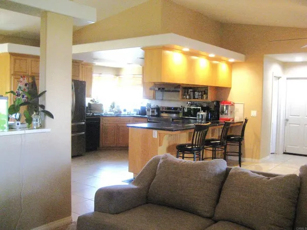a living room with stainless steel appliances kitchen island granite countertop furniture and a large window