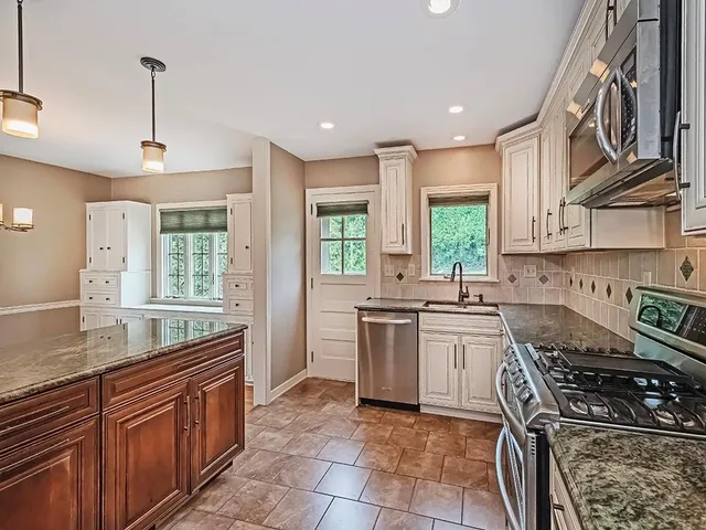 a kitchen with stainless steel appliances granite countertop a stove a sink and a refrigerator