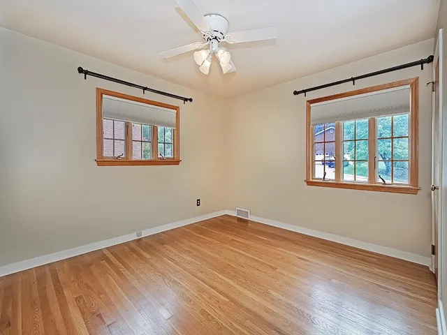 a view of an empty room with window and wooden floor