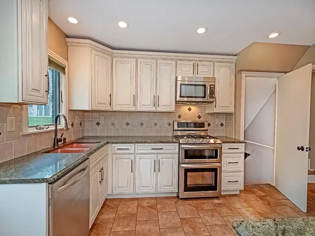 a kitchen with stainless steel appliances granite countertop a stove a sink and a refrigerator