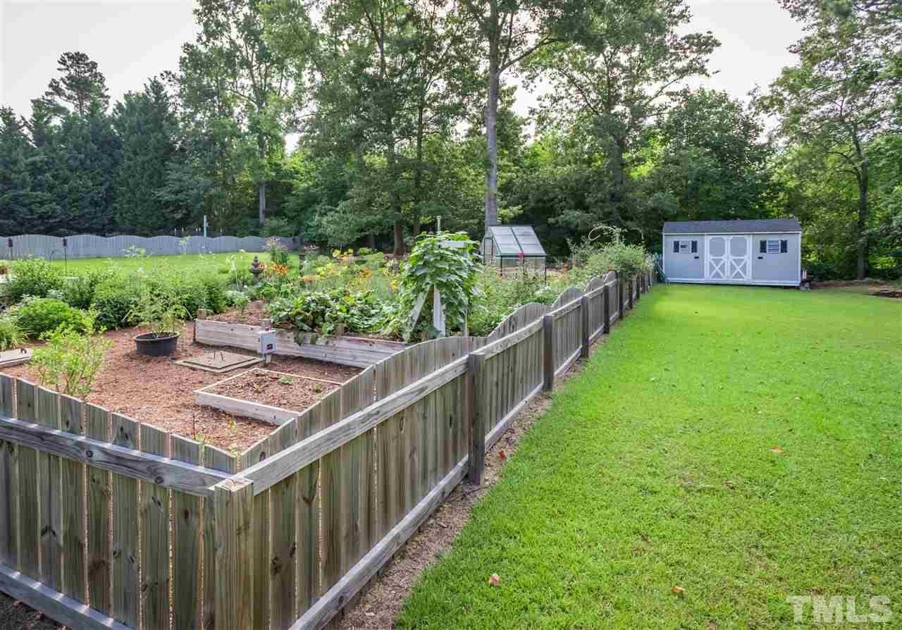4017 Forty-Niner's Road Clayton, NC 27520 - Photo 24 of 25 Majority of Backyard with Perennial and Vegetable Garden is Fenced with Double Gate Leading to Detached Shed and Trees Bordering Property