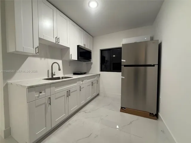a kitchen with sink a refrigerator and cabinets