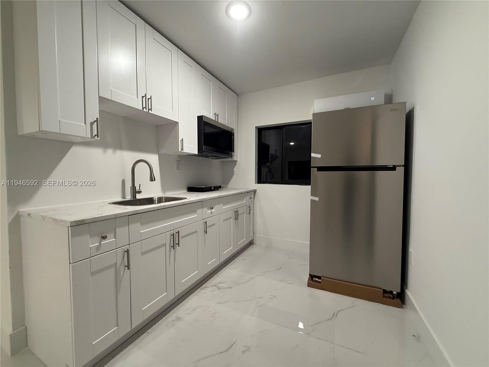 450 Beacom Boulevard, Unit C Miami, FL 33135 - Photo 2 of 9 a kitchen with sink a refrigerator and cabinets