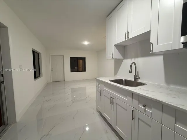 a kitchen with white cabinets a sink and dishwasher