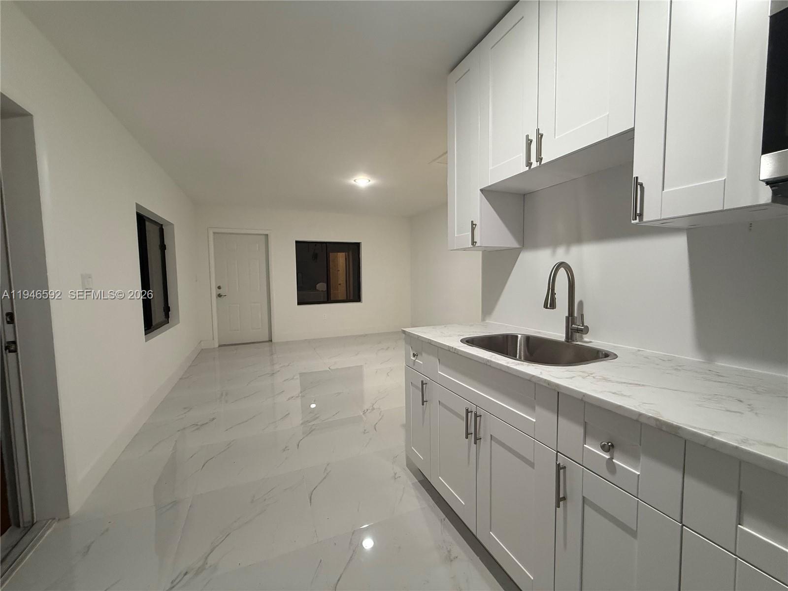 450 Beacom Boulevard, Unit C Miami, FL 33135 - Photo 3 of 9 a kitchen with white cabinets a sink and dishwasher