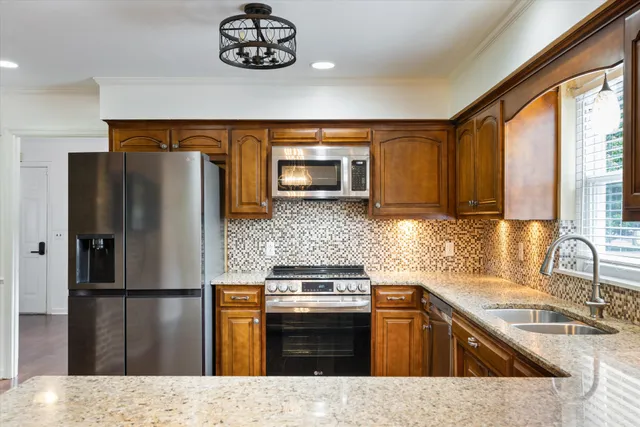 a large kitchen with granite countertop a large counter top and stainless steel appliances
