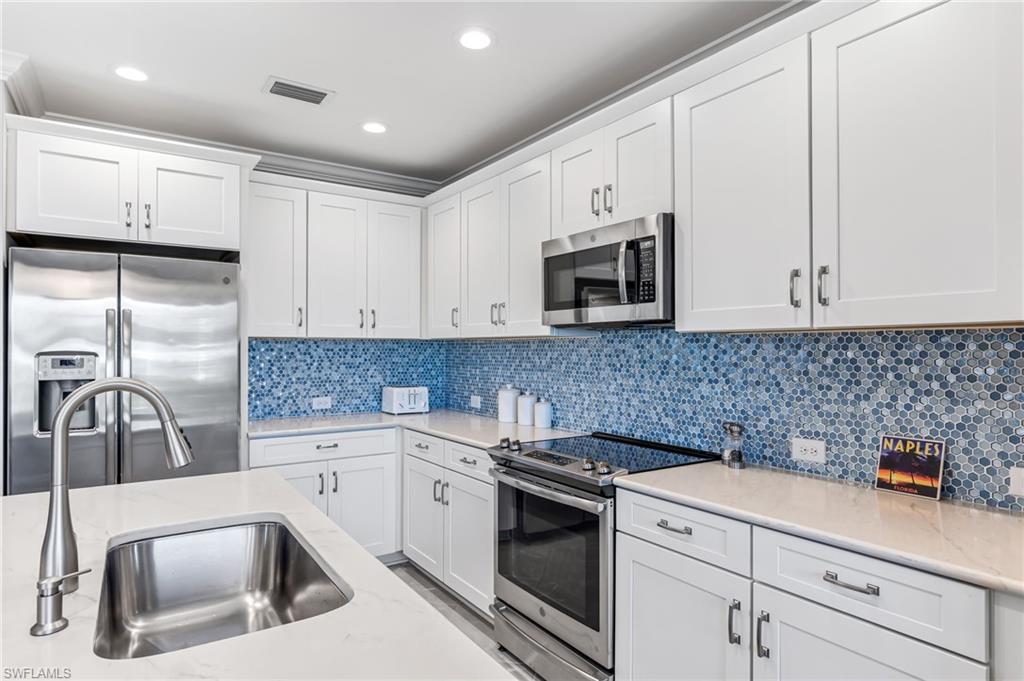 6948 Avalon Circle, Unit 604 Naples, FL 34112 - Photo 12 of 33 Kitchen with tasteful backsplash, appliances with stainless steel finishes, a sink, and white cabinetry