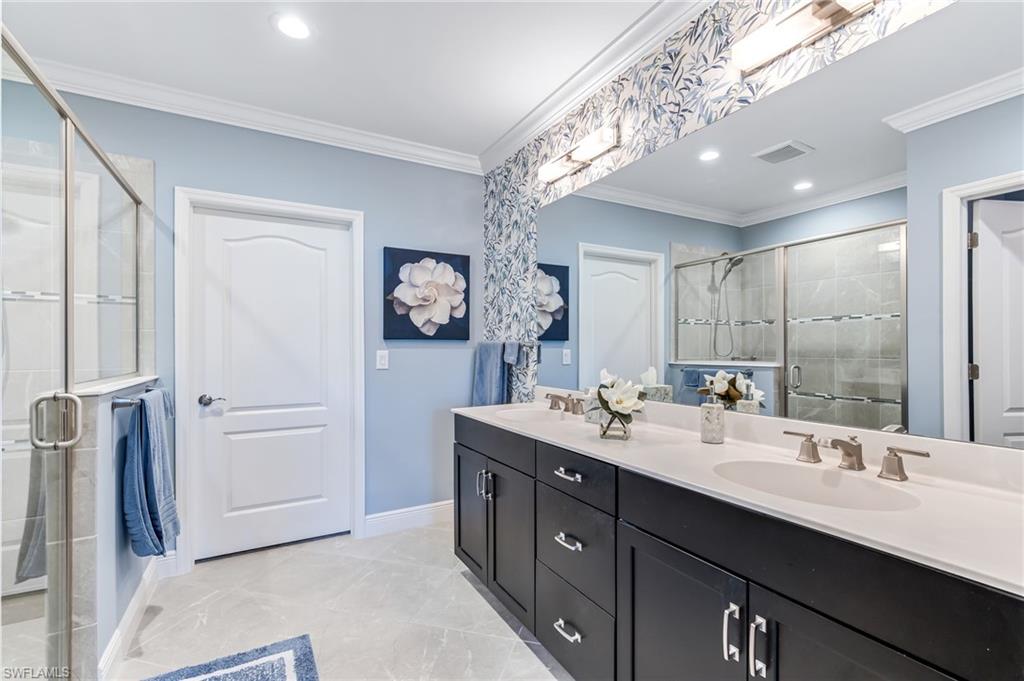 6948 Avalon Circle, Unit 604 Naples, FL 34112 - Photo 18 of 33 Full bathroom with double vanity, a sink, a stall shower, and crown molding
