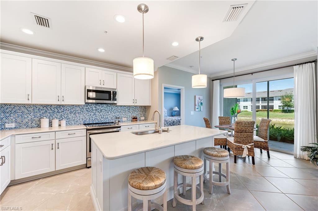 6948 Avalon Circle, Unit 604 Naples, FL 34112 - Photo 8 of 33 Kitchen featuring a sink, appliances with stainless steel finishes, crown molding, decorative backsplash, and light tile patterned flooring