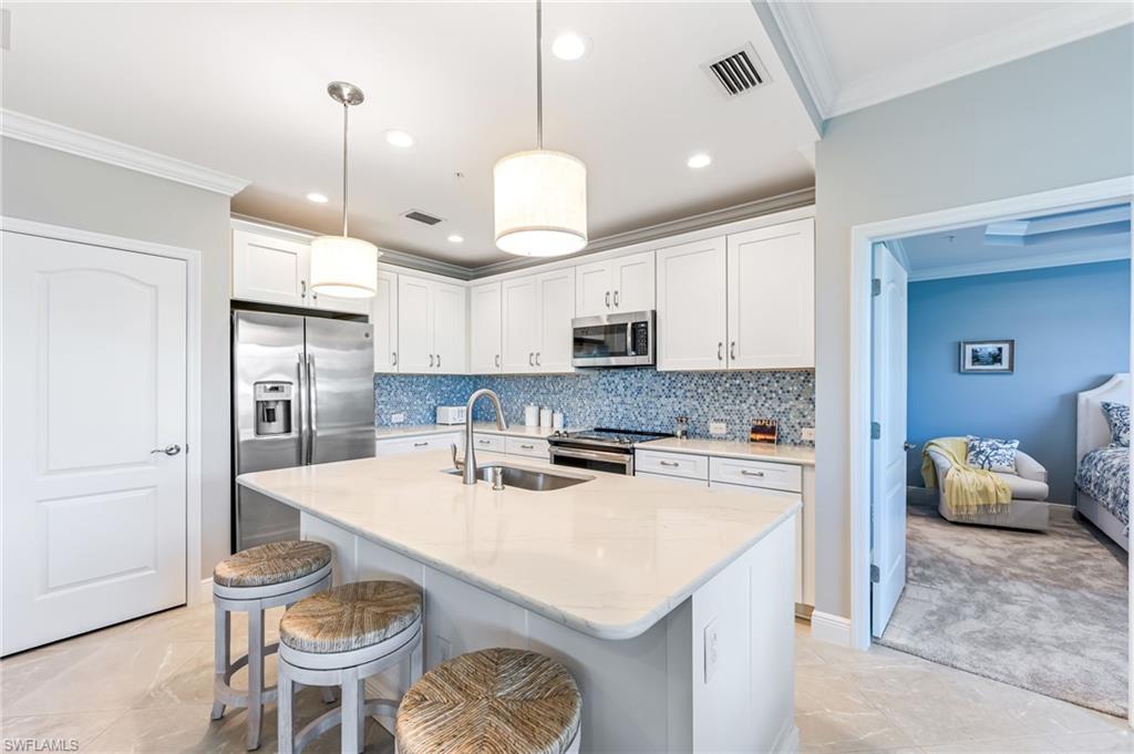 6948 Avalon Circle, Unit 604 Naples, FL 34112 - Photo 9 of 33 Kitchen featuring a kitchen bar, ornamental molding, visible vents, appliances with stainless steel finishes, and a sink