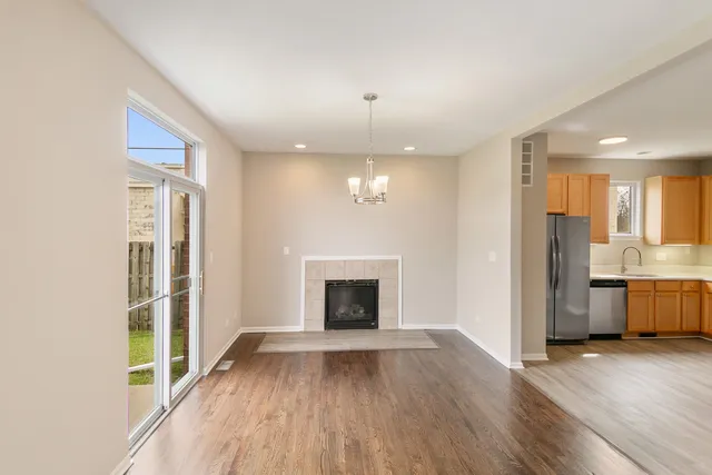 an empty room with wooden floor fireplace and windows