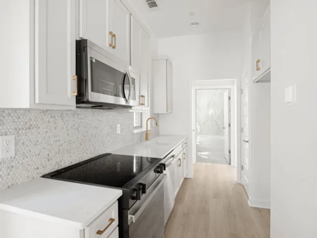 a kitchen with stainless steel appliances a stove microwave and sink