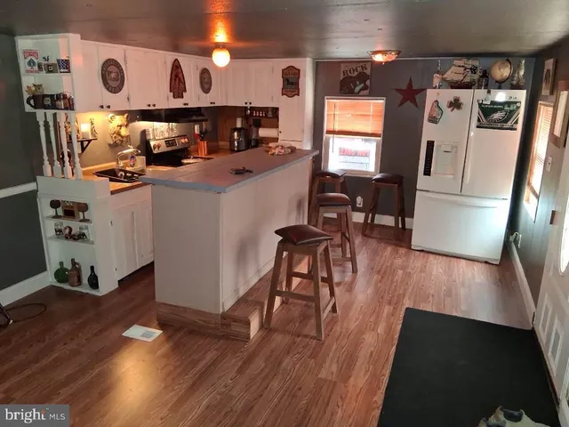 a kitchen with stainless steel appliances a refrigerator and wooden floor