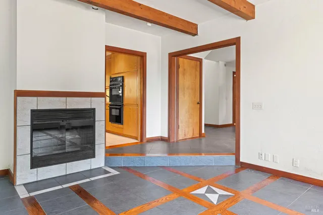 a view of an empty room with wooden floor and a fireplace