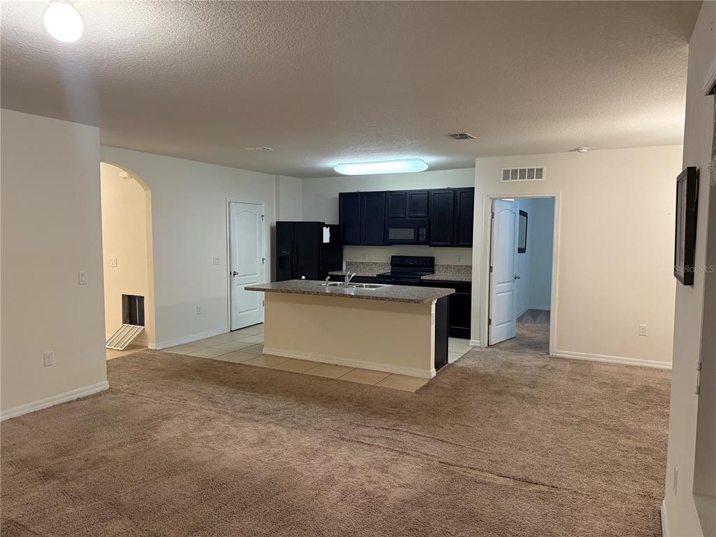 1895 Hickory Bluff Road Kissimmee, FL 34744 - Photo 3 of 17 a kitchen with stainless steel appliances kitchen island a refrigerator sink and microwave