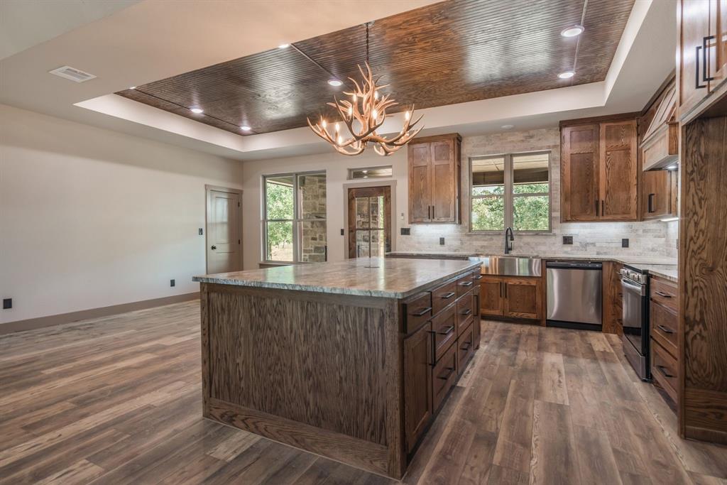 233 Jayden Lane Loving, TX 76460 - Photo 11 of 40 a large kitchen with stainless steel appliances granite countertop a lot of counter space and wooden floors