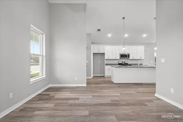 a view of kitchen with kitchen island granite countertop a stove a sink and white cabinets