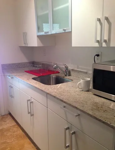 a kitchen with white cabinets and sink