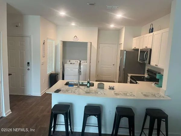 a kitchen with stainless steel appliances granite countertop a dining table chairs refrigerator and sink