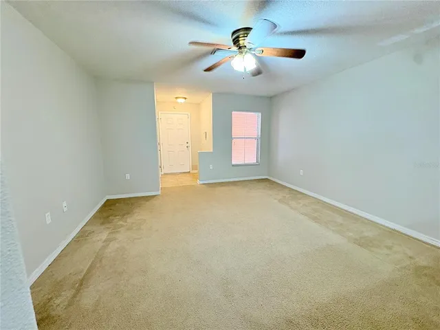 an empty room with windows and chandelier fan