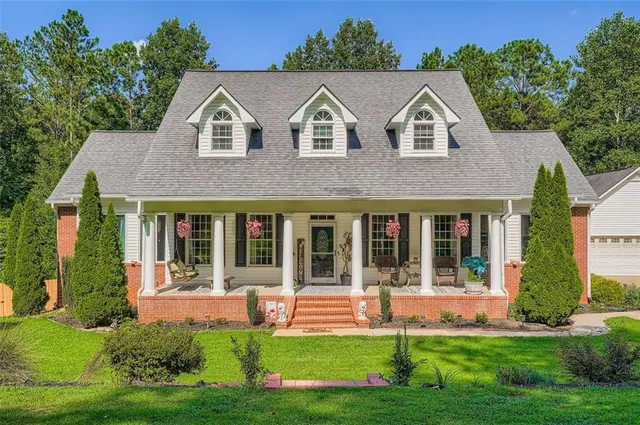 a view of a white house with a big yard and potted plants and large trees