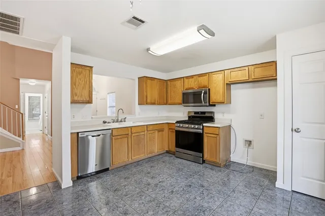 a kitchen with granite countertop a refrigerator stove top oven a sink and dishwasher