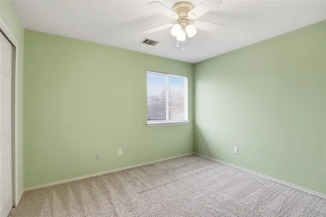 an empty room with a window and a ceiling fan