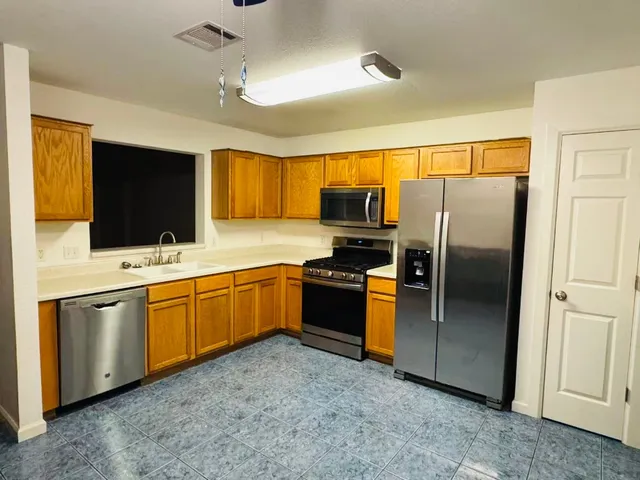 a kitchen with stainless steel appliances granite countertop a refrigerator a sink dishwasher a oven with wooden cabinets and outdoor view