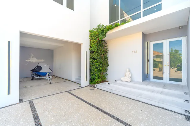 a view of a white house with plants and large trees