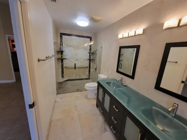 a bathroom with a double vanity sink toilet and mirror