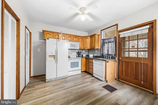 a kitchen with granite countertop wooden floors a refrigerator and a sink