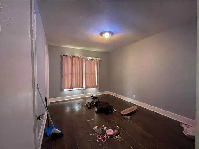 an empty room with wooden floor and a ceiling fan