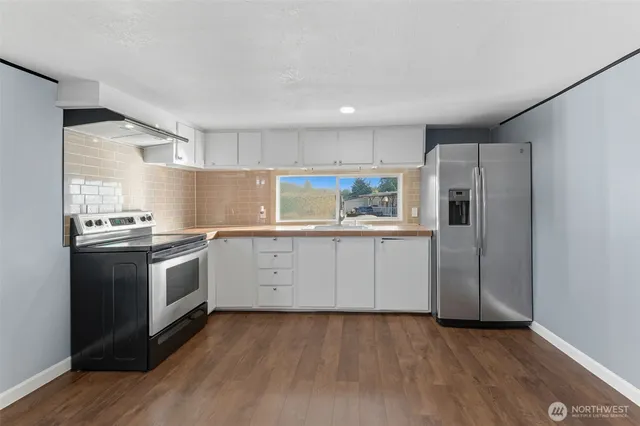 a kitchen with granite countertop white cabinets and stainless steel appliances