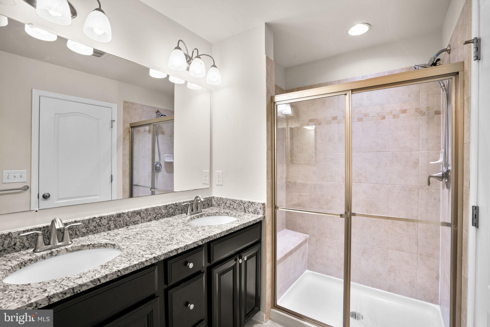 7977 Alchemy Way Elkridge, MD 21075 - Photo 17 of 33 a bathroom with a granite countertop sink a large mirror and a shower