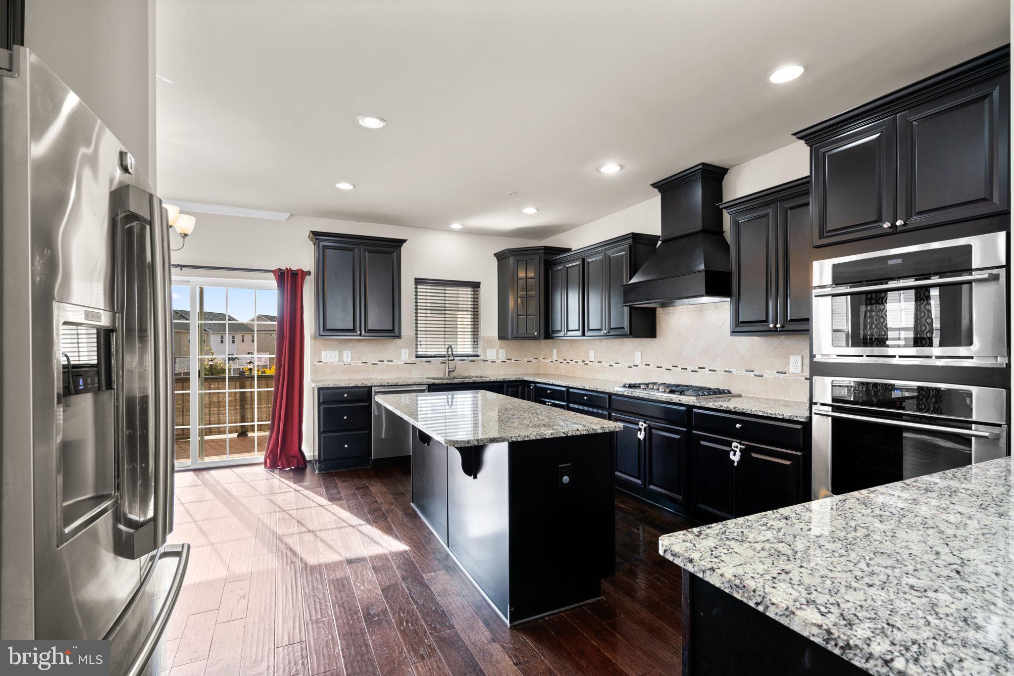 7977 Alchemy Way Elkridge, MD 21075 - Photo 6 of 33 a kitchen with stainless steel appliances kitchen island granite countertop a stove refrigerator and cabinets