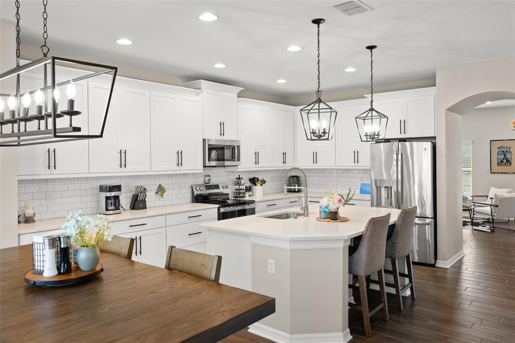 1216 Multiflora Loop Lutz, FL 33558 - Photo 11 of 50 a kitchen with cabinets a stove a sink a dining table and chairs