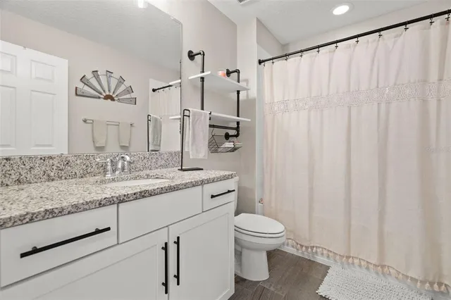 a bathroom with a granite countertop sink a toilet and a mirror