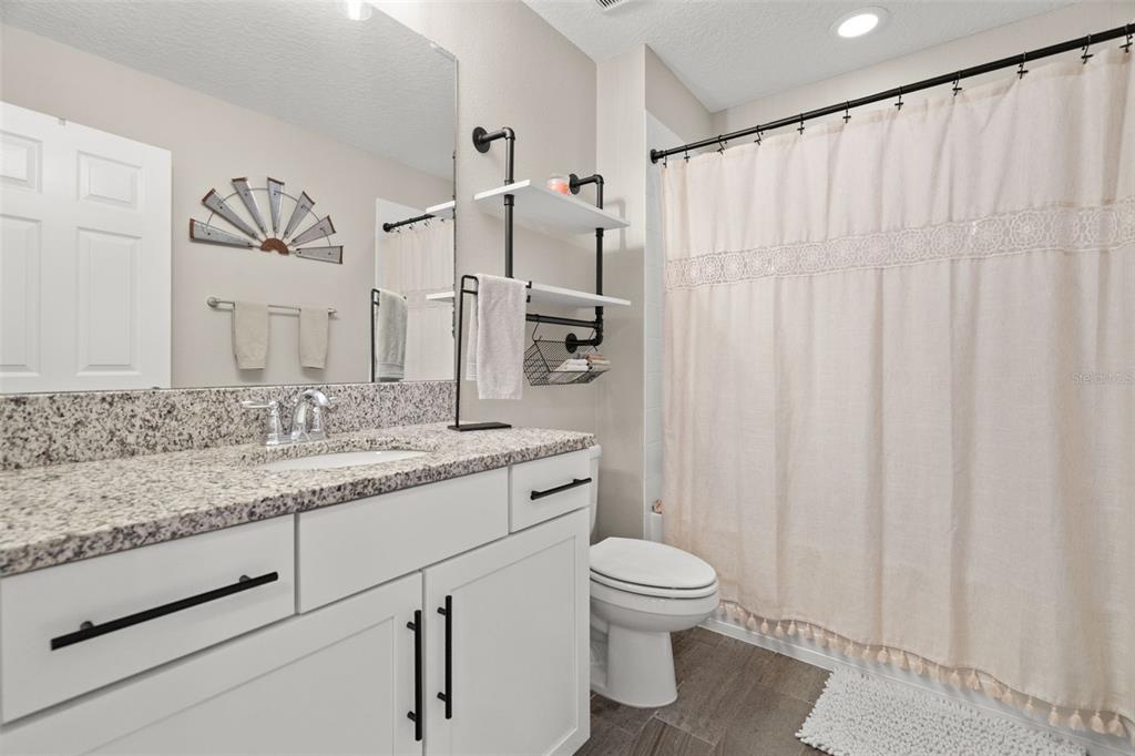1216 Multiflora Loop Lutz, FL 33558 - Photo 24 of 50 a bathroom with a granite countertop sink a toilet and a mirror