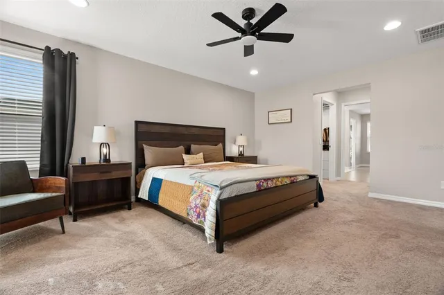 a bed sitting in a spacious bedroom next to a window