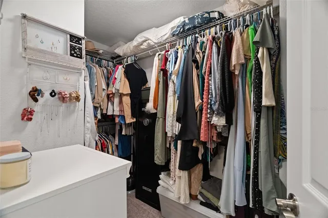 a view of walk in closet with clothes and shoes