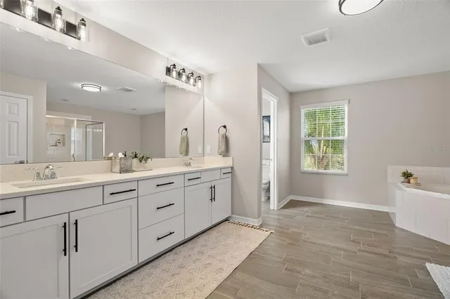 a spacious bathroom with a granite countertop sink mirror and a bathtub