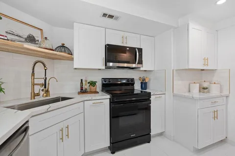 a kitchen with white cabinets stainless steel appliances and a sink