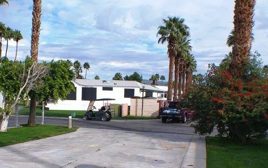 a view of a white house with a small yard and palm trees