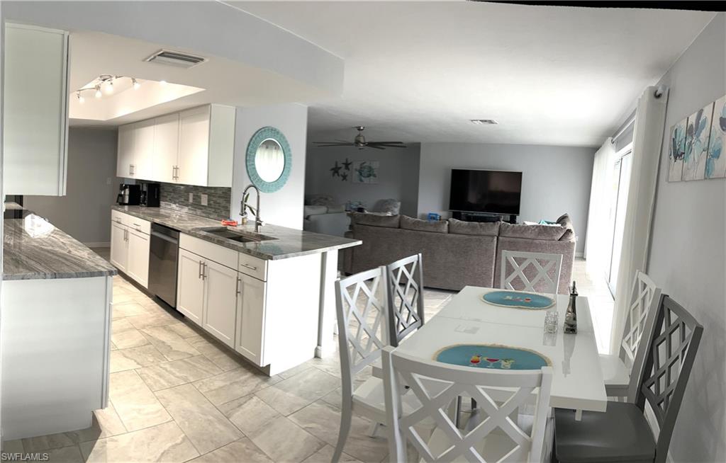 13511 Island Road Fort Myers, FL 33905 - Photo 13 of 38 a kitchen with stainless steel appliances granite countertop a stove top oven a sink dishwasher a dining table and chairs with wooden floor
